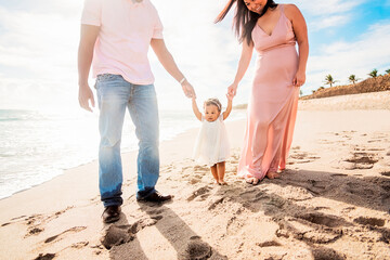 Couple holding hands of baby daughter walking on beach