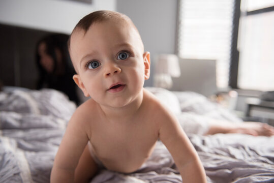 Curious Caucasian baby boy crawling on bed