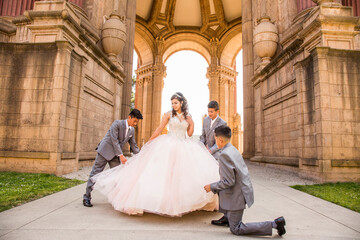 Hispanic boys holding skirt of girl