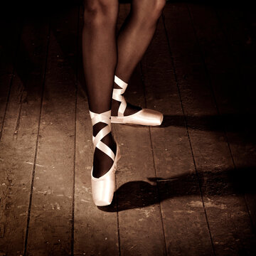 Legs of Caucasian ballerina standing on wooden floor