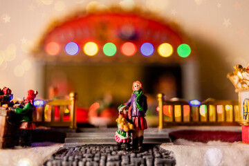 miniature scene of mother and daughter in Christmas amusement park with colored lights - traditional decoration figure