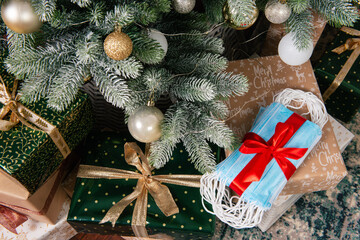 Face medical blue masks wrapped with a red ribbon under a christmas tree. New Year concept during coronavirus theme.