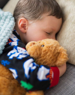 Boy (6-7) holding teddy bear during sleep