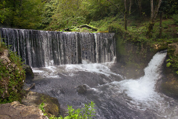 Obraz premium Beautiful nature, tourism, summer landscape, green grass and trees, river and mountains, waterfall