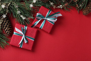 Two Christmas giftbox of red paper with ribbons on red surface. Holiday card. Top view. Copy space