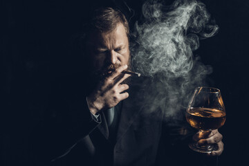 Solid confident bearded man in suit with glass of whisky and cigar with fume