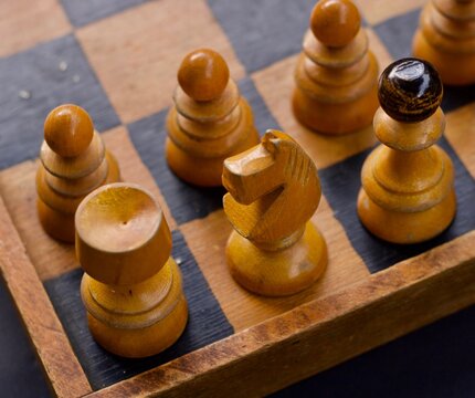 Vintage Wooden Chess Board with colored wooden black and natural wood figures. Pawns, queen, bishop, horse, the rook.