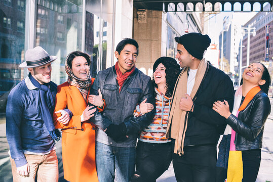 Six Millennial friends walk arm in arm in they city during cold weather - Holidays - Concept Good times
