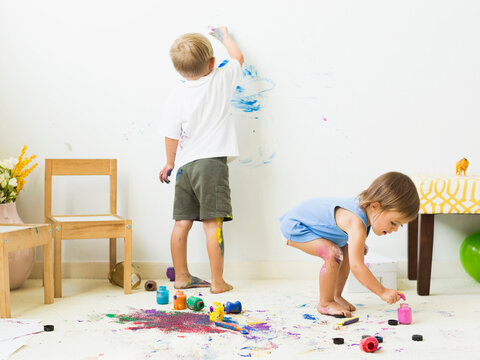Children (2-3) painting on carpet and wall