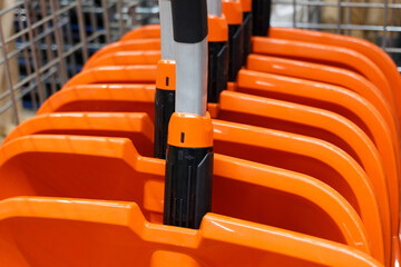 Shopping basket with orange plastic wide snow scrapers. Soft focus, close-up.