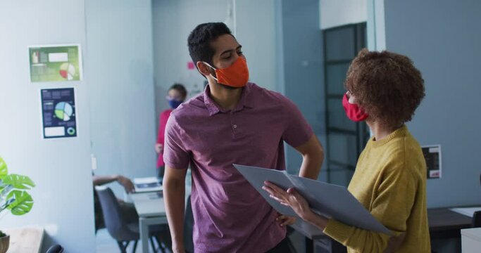 Mixed race man and woman wearing face masks in office