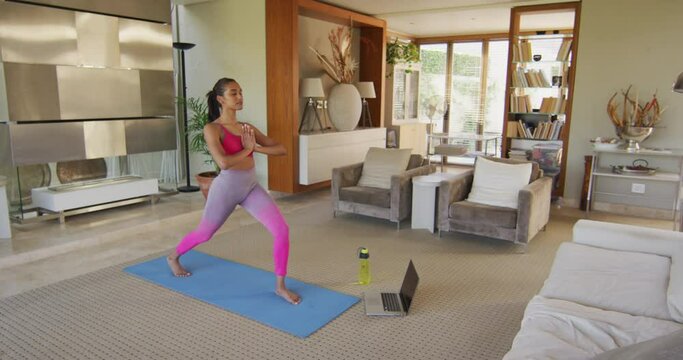 Mixed race woman practising yoga at home