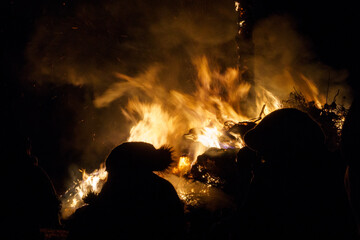 Silhouette of people standing in front of a big fire