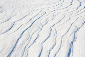 Beautiful winter background with snowy ground. Natural snow texture. Wind sculpted patterns on snow surface. Arctic, Polar region.