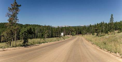 Panorama shot of clay wide road comming to Rocky mountain with remnants of snow