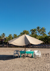 table with umbrella on the shore of the beautiful beach with palm trees in the background, no people