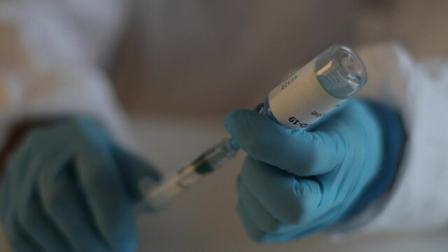 Concept of Covid 19 vaccine vaccinating, development and creation, doctor or scientist in laboratory holding a single dose of  2019-ncov vaccine, a syringe and ampule with SARS-CoV-2 vaccination