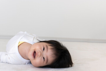 寝返り途中でカメラ目線の赤ちゃん(0歳、生後5か月、女の子)