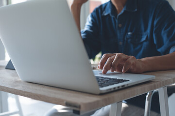 Business man online working on laptop computer surfing the internet from home office