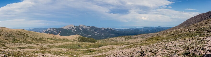 Panorama shot of green rocky hills with remnants of snow in Rocky mountains national park in america