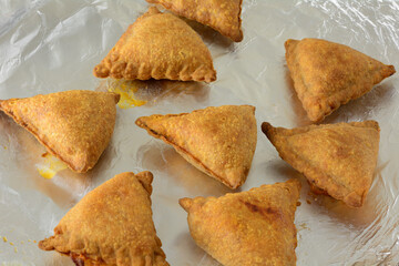 Hot out of the oven Baked samosa snacks or appetizers on aluminum foil on baking sheet