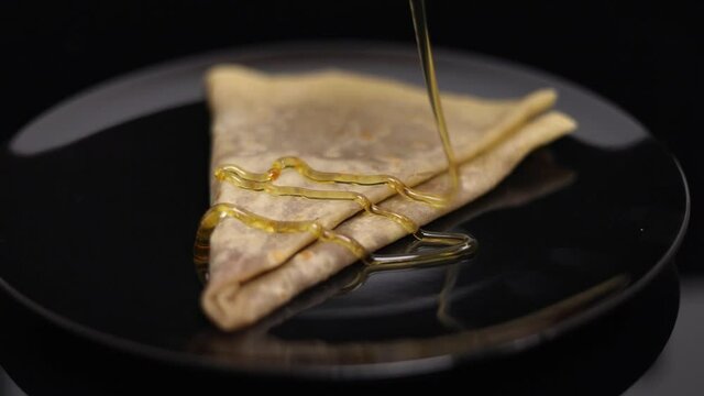 Honey over a freshly baked crepe - slow motion close up shot