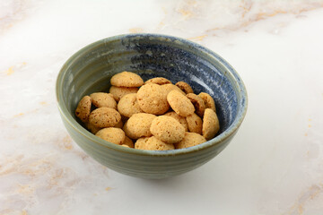 Italian amarettini almond mini cookies in ceramic snack bowl on table