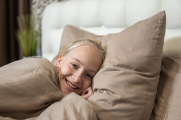 Teenage girl with blond hair woke up in bed