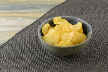 Italian black truffle potato chips in ceramic snack bowl on burlap table runner on table