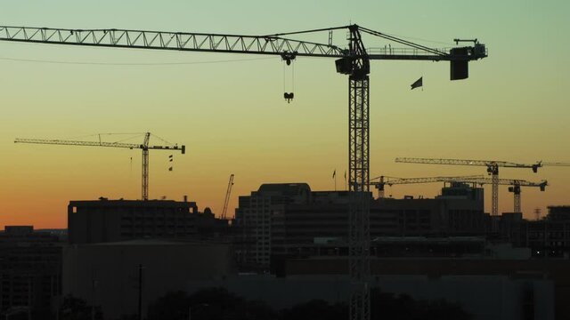 birds fly past sky crane lift building construction site silhouette at sunset