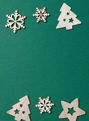 Christmas composition vertical. Border made of wooden Xmas decorations up and down on green background. Greeting card concept, winter holiday wishes template. Top view, copy space.