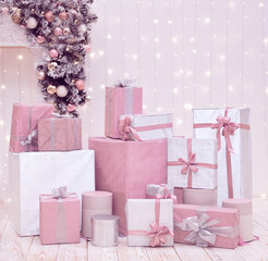 Christmas wrapped pink and white gift boxes on pastel background with holiday decorations and lights. Xmas shopping, presents concept.