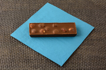 Hazelnut milk chocolate candy bar on blue napkin on burlap