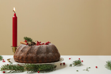Festive decorated bundt cake with red berries on the light ochre background.
