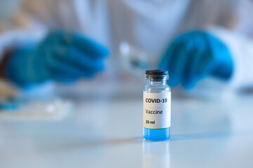 Concept of Covid 19 vaccine vaccinating, development and creation, doctor or scientist in laboratory holding a single dose of  2019-ncov vaccine, a syringe and ampule with SARS-CoV-2 vaccination