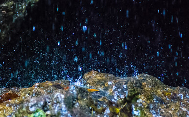 Water flows through rocks in the cave. A small waterfall at the entrance to the cave.