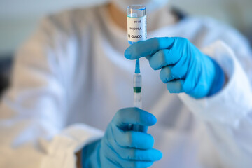 Concept of Covid 19 vaccine vaccinating, development and creation, doctor or scientist in laboratory holding a single dose of  2019-ncov vaccine, a syringe and ampule with SARS-CoV-2 vaccination