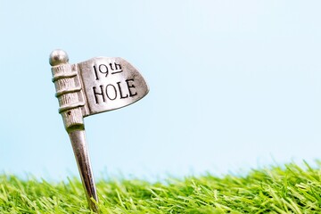 Golf 19th Hole on green grass with blue sky background