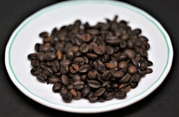 Coffee beans on a white saucer.
