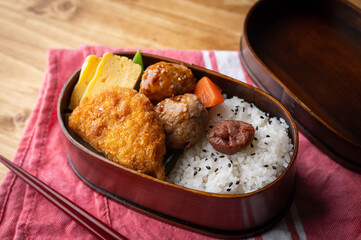 japanese style bento in wooden box with meat ball and croquette