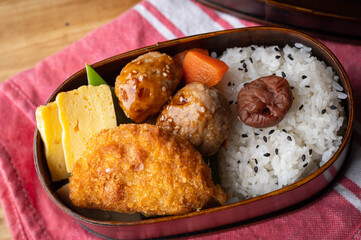 japanese style bento in wooden box with meat ball and croquette