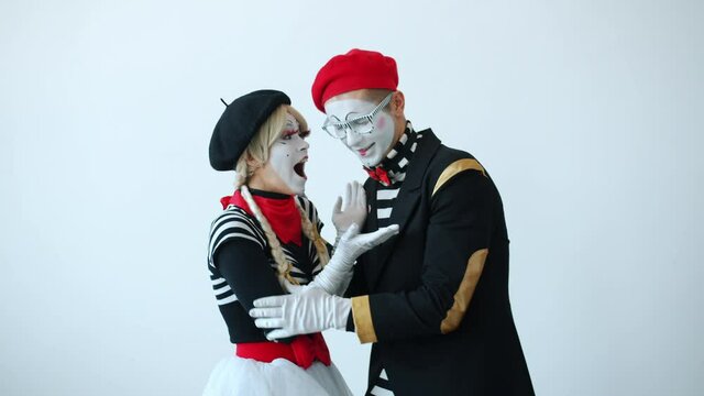 Portrait of funny mimes man and woman talking and hugging expressing love then looking at camera smiling on white background. Relationship and people concept.