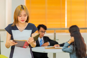 Modern attractive teacher. Portrait of Beautiful smart young asian woman with book standing in library. Study concept