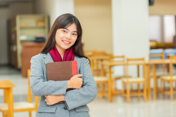 Happy young university students studying with books in library.