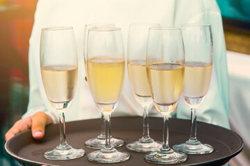 Operation served champagne and water glasses on a tray. (lens blur effect and vintage color tone)