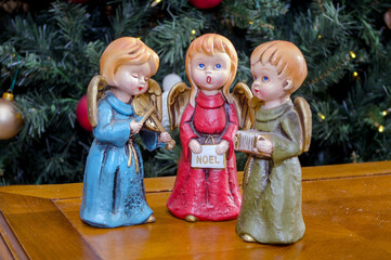trio of  Christmas angels with instruments in front of a Christmas tree