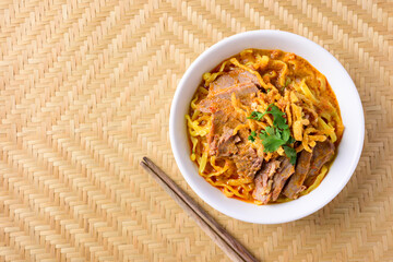 Northern Thai food (Khao Soi), Spicy curry noodles soup with beef in a bowl and chopsticks, Top view