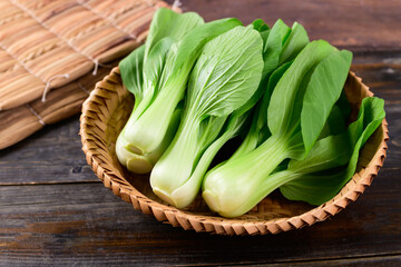 Fresh Bok Choy or Pak Choi (Chinese cabbage) in bamboo basket on wooden background, Organic vegetables