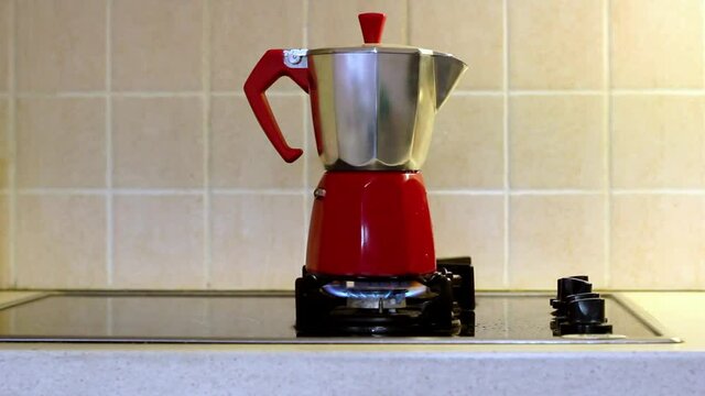 Red Italian geyser coffee maker on home gas stove.