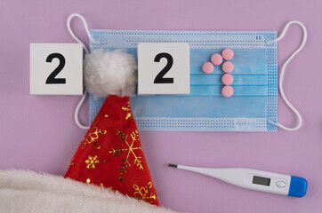 Santa Claus hat, surgical medical mask and numbers 2021. medical Christmas. celebration in the period of pandemic coronavirus. respiratory bandage face and thermometer. upper view